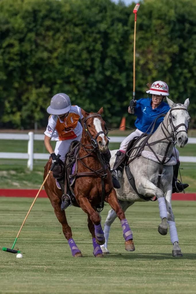 Apollo Team polo player in an orange Tall Builders jersey riding for the ball beside an opponent