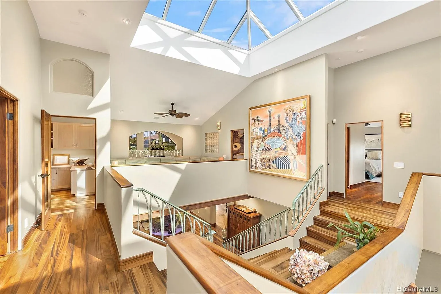 Sunlit upper landing of a Tall Builders luxury home renovation with skylight, koa-toned floors, and open staircase